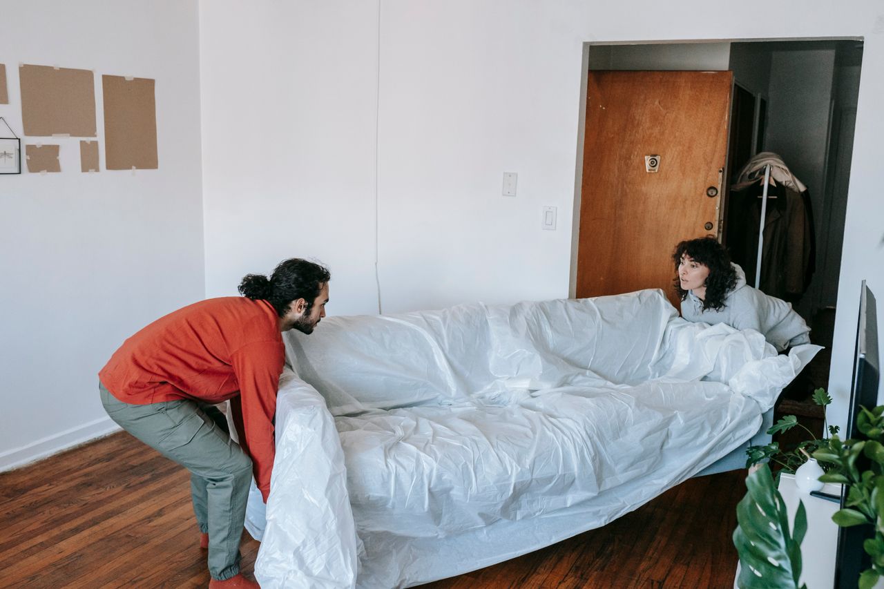 services-03 A couple collaboratively lifting a couch while moving into a new apartment.