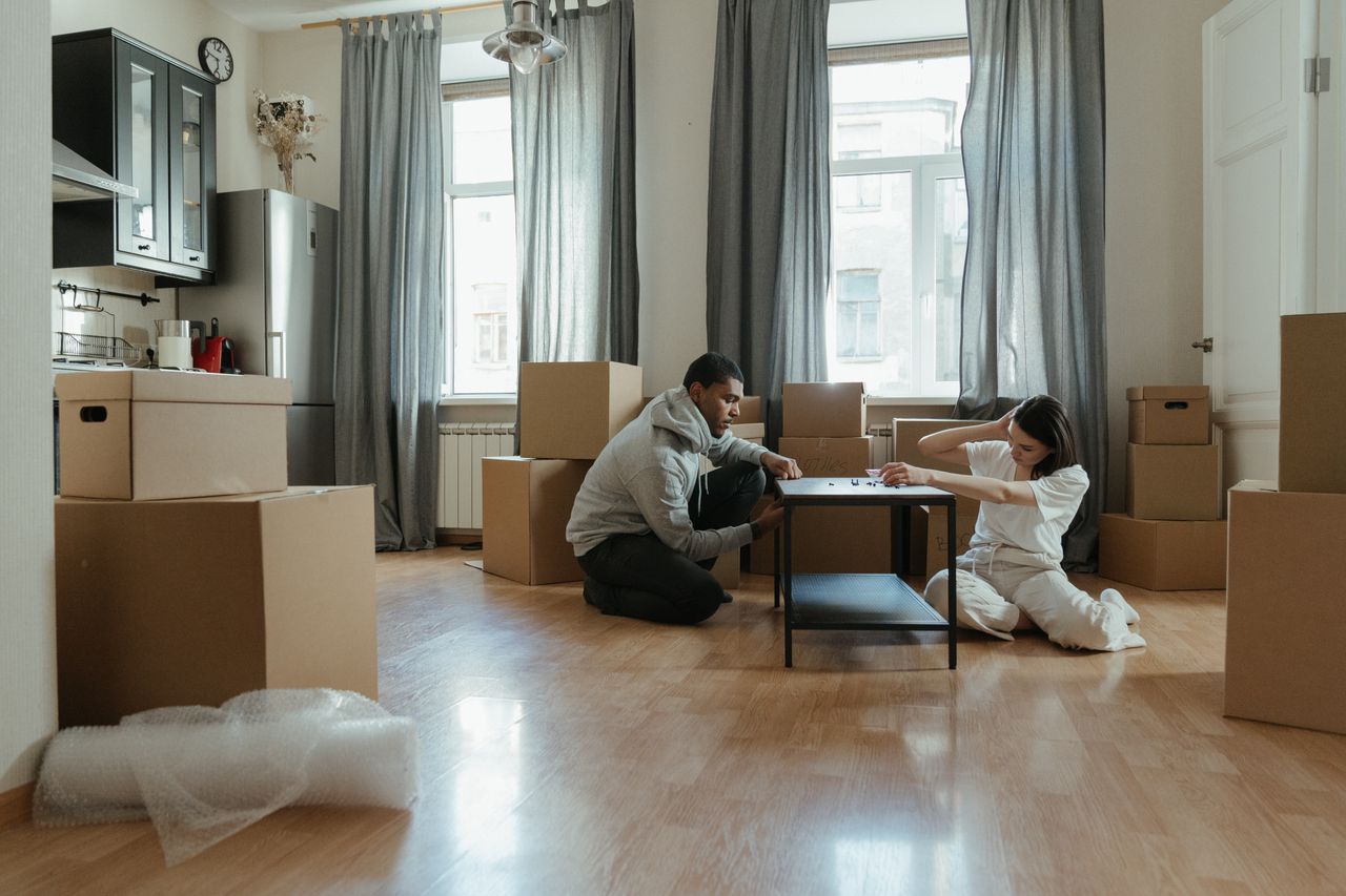 why-choose-us Young couple assembling furniture in their new apartment, surrounded by cardboard boxes.
